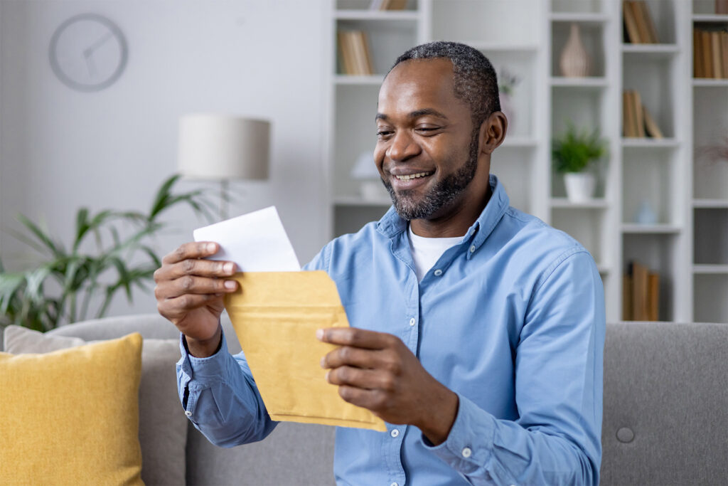 Joyful man receiving real estate postcards in mail
